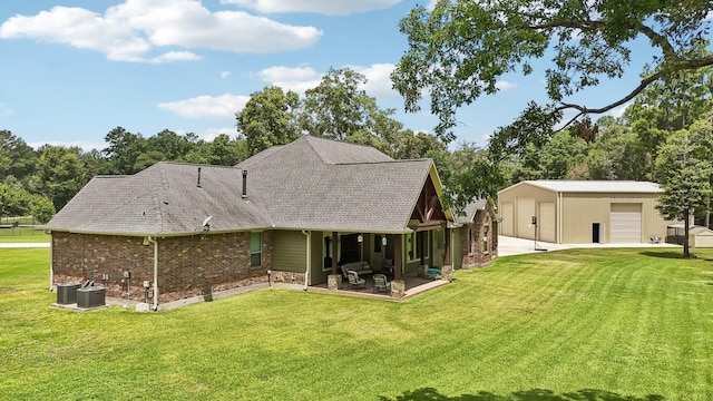 back of property with an outbuilding, brick siding, a lawn, and a detached garage