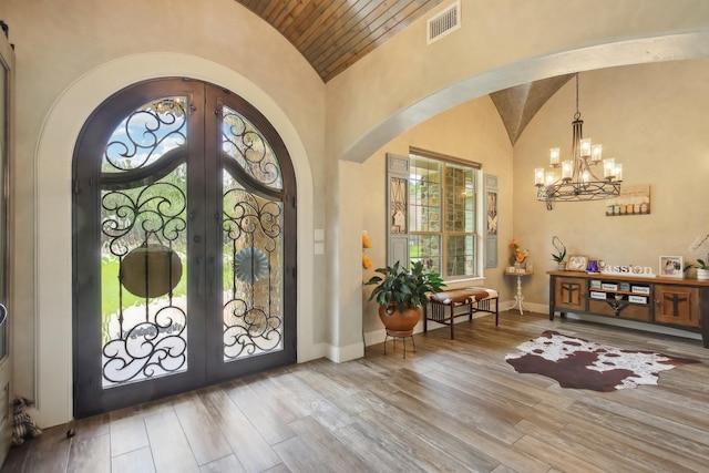 entryway featuring arched walkways, vaulted ceiling, wood finished floors, and french doors