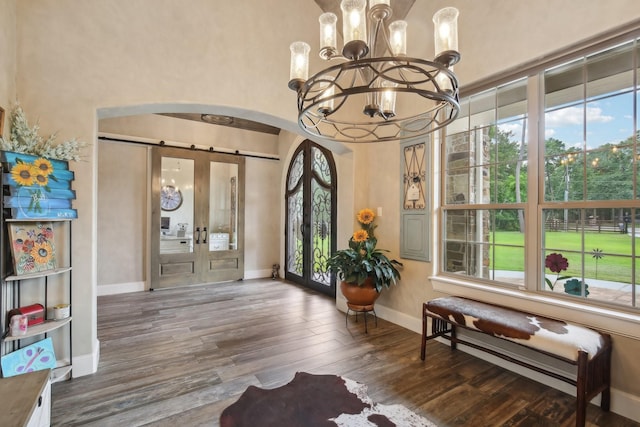 interior space with plenty of natural light, arched walkways, a chandelier, and wood finished floors