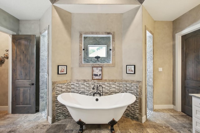 bathroom with a soaking tub, tile walls, baseboards, and vanity