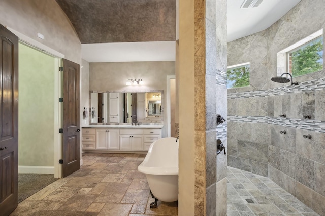 bathroom with a walk in shower, a freestanding tub, stone tile floors, visible vents, and vanity