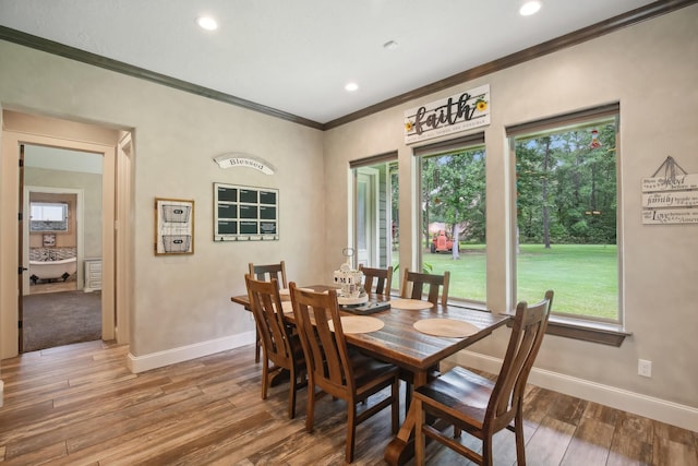 dining room featuring a wealth of natural light, crown molding, baseboards, and wood finished floors