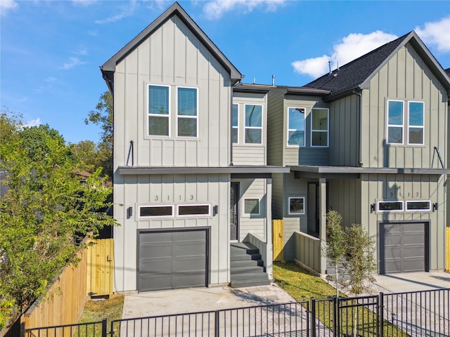 view of front of home featuring driveway, board and batten siding, an attached garage, and fence private yard