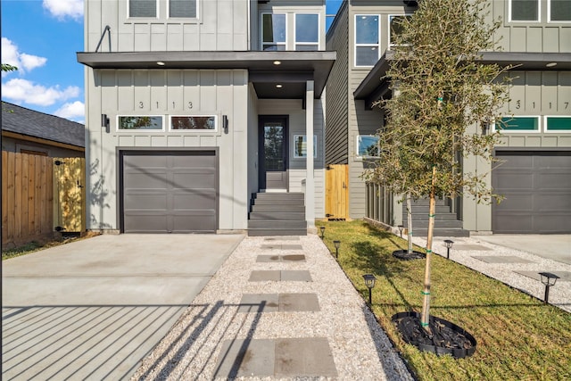 view of front of property with board and batten siding, concrete driveway, fence, and an attached garage