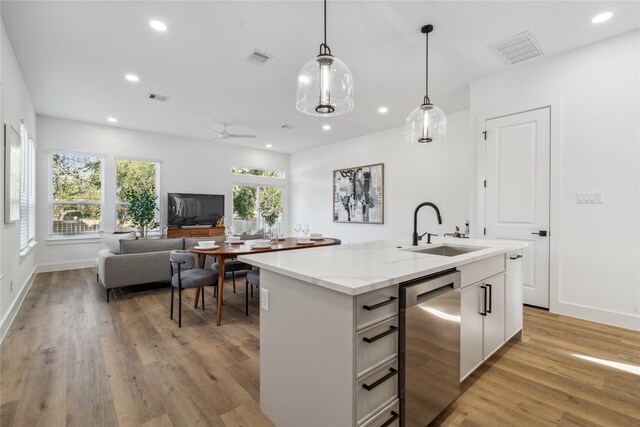 kitchen with a sink, white cabinets, open floor plan, dishwasher, and a center island with sink