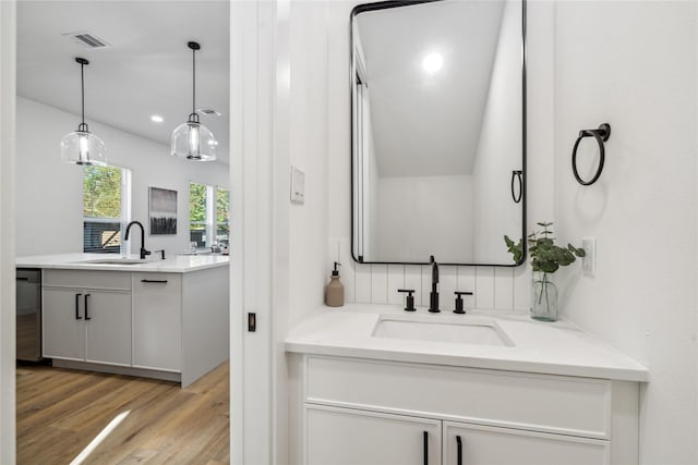 bathroom with visible vents, two vanities, a sink, and wood finished floors