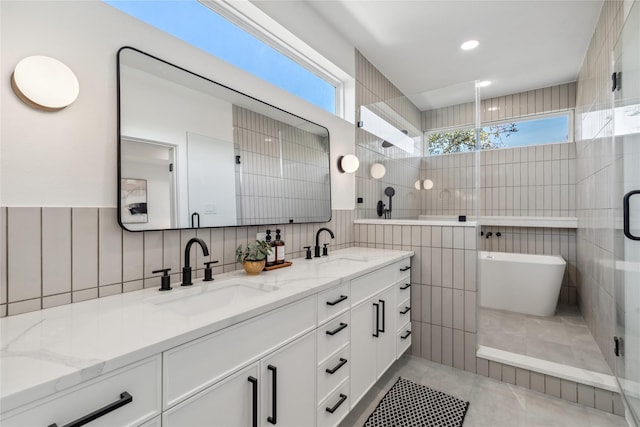 full bathroom with plenty of natural light, a sink, tile walls, and double vanity