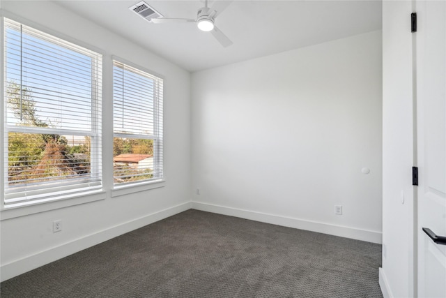 unfurnished room with a ceiling fan, dark colored carpet, visible vents, and baseboards