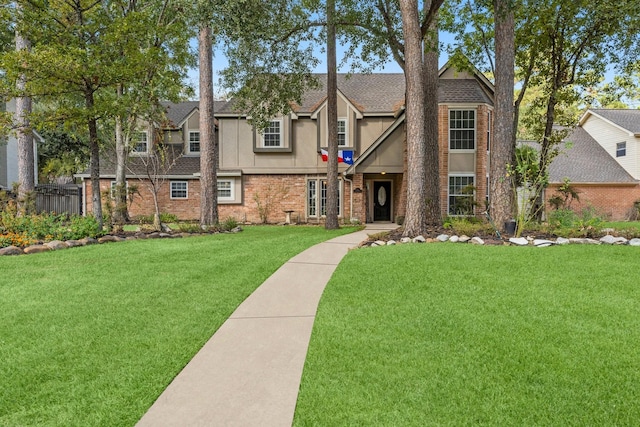 view of front facade featuring brick siding, roof with shingles, a residential view, stucco siding, and a front yard