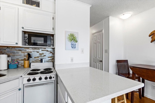 kitchen featuring black microwave, a peninsula, electric range, white cabinets, and light countertops