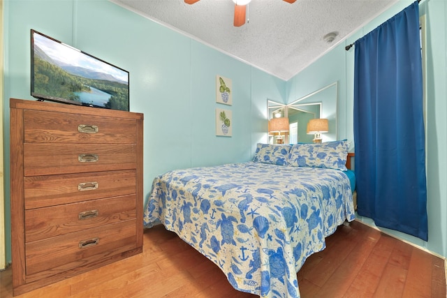 bedroom with a textured ceiling, ceiling fan, and light wood-style floors