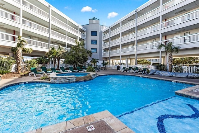 view of swimming pool featuring a pool with connected hot tub and fence