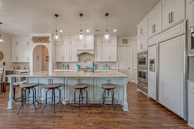 kitchen with white cabinetry, arched walkways, and stainless steel double oven