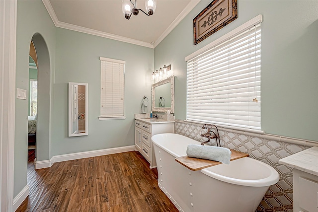 bathroom featuring a wainscoted wall, vanity, wood finished floors, a freestanding bath, and crown molding