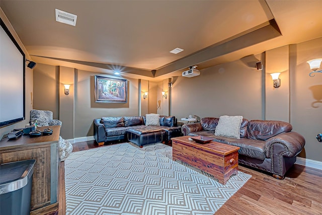 living room featuring a raised ceiling, visible vents, and wood finished floors