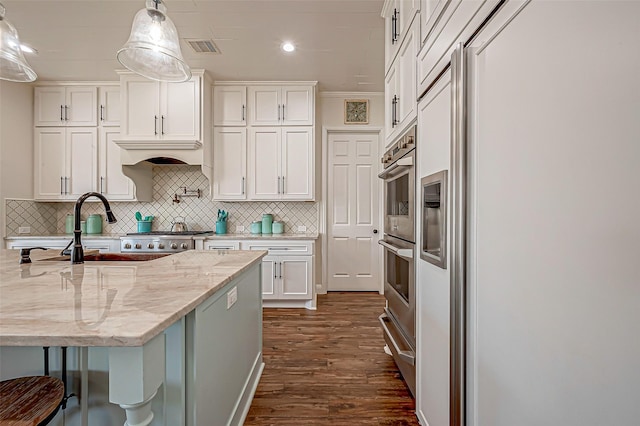 kitchen with paneled fridge, light stone counters, dark wood-style flooring, white cabinetry, and decorative backsplash