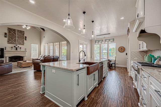 kitchen with arched walkways, a fireplace, backsplash, dark wood-type flooring, and a sink