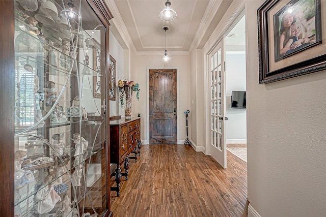 foyer entrance featuring french doors, a textured wall, ornamental molding, wood finished floors, and baseboards