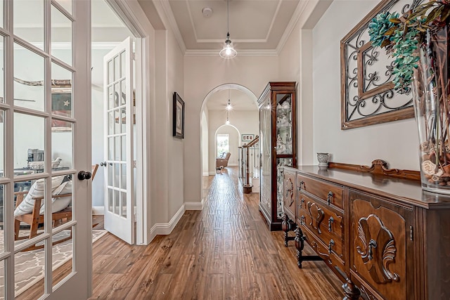 interior space with arched walkways, french doors, crown molding, wood finished floors, and baseboards