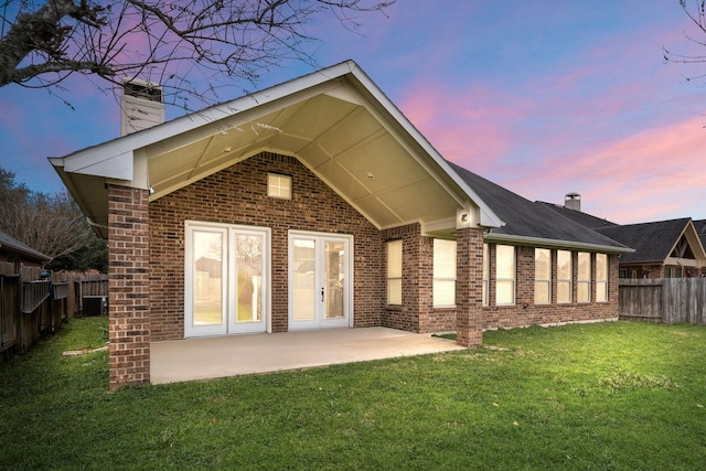 back of property at dusk with brick siding, a chimney, and fence