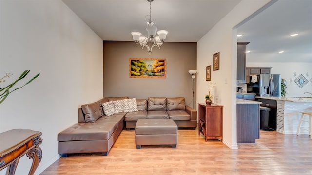 living area with baseboards, recessed lighting, light wood-style flooring, and a notable chandelier