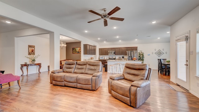 living room with ceiling fan with notable chandelier, light wood-type flooring, and recessed lighting