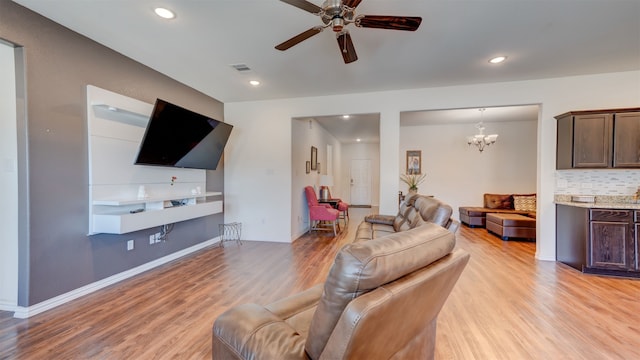 living room with recessed lighting, visible vents, light wood-style flooring, baseboards, and ceiling fan with notable chandelier