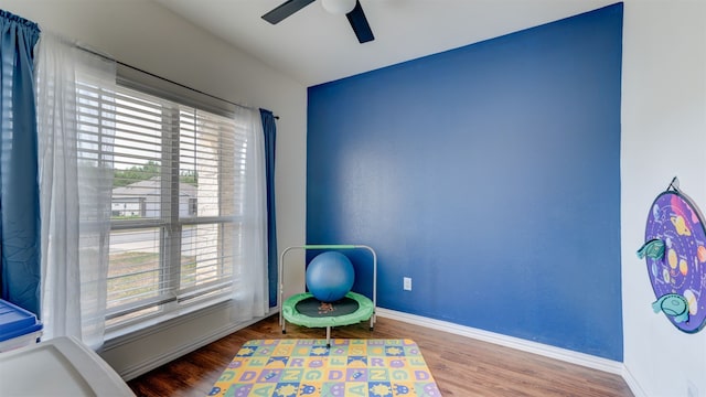 playroom with a ceiling fan, plenty of natural light, baseboards, and wood finished floors