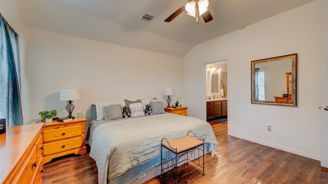 bedroom featuring baseboards, visible vents, ensuite bath, dark wood-style flooring, and vaulted ceiling