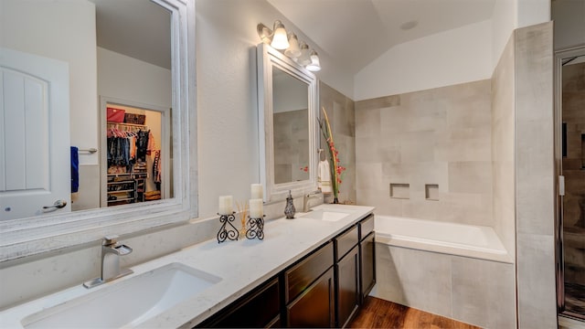 full bathroom featuring a bath, double vanity, vaulted ceiling, and a sink