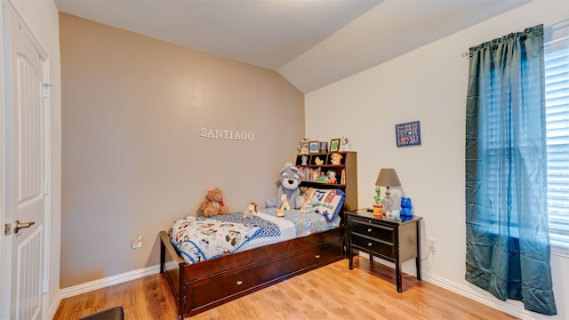 bedroom featuring vaulted ceiling, baseboards, and wood finished floors