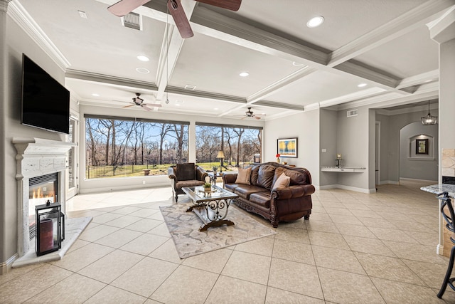 living area featuring a glass covered fireplace, coffered ceiling, ceiling fan, and light tile patterned floors