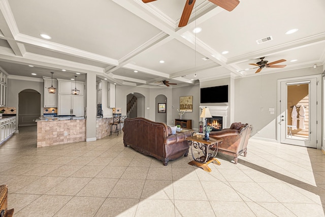 living area featuring arched walkways, a lit fireplace, coffered ceiling, and recessed lighting