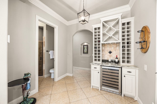 bar featuring beverage cooler, ornamental molding, baseboards, and light tile patterned flooring