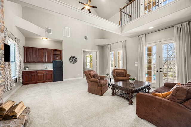 living area featuring light carpet, visible vents, and french doors