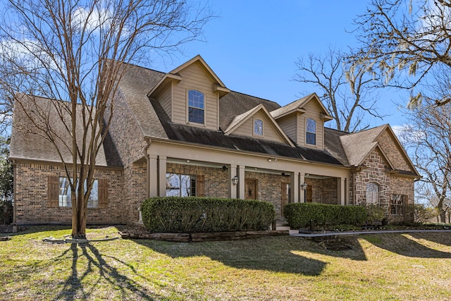 view of front of home with brick siding, a front lawn, and roof with shingles