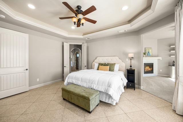 bedroom featuring a raised ceiling, visible vents, light tile patterned flooring, a lit fireplace, and baseboards