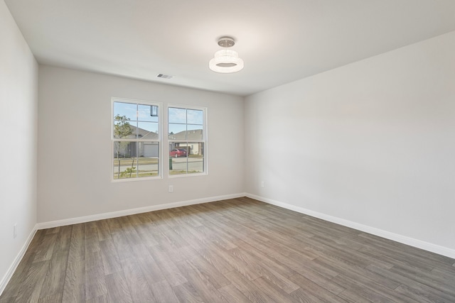 spare room featuring baseboards, visible vents, and wood finished floors