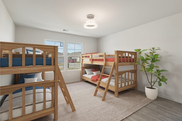 bedroom with light wood-style floors, visible vents, and baseboards