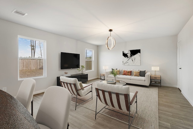 living room featuring baseboards, wood finished floors, visible vents, and a healthy amount of sunlight