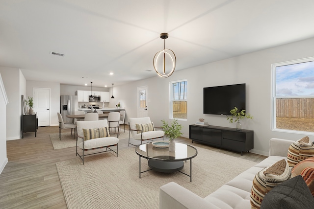 living room with baseboards, light wood-type flooring, visible vents, and recessed lighting