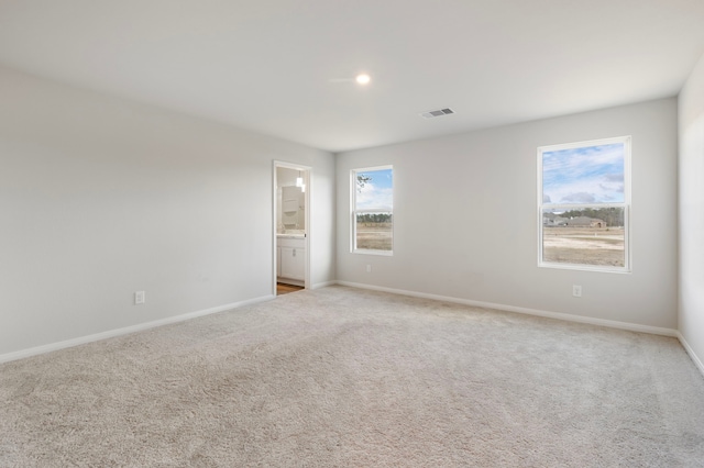 empty room featuring light colored carpet, visible vents, and baseboards