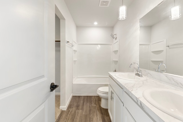 bathroom featuring toilet, wood finished floors, a sink, and visible vents