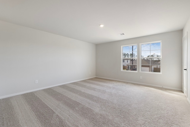 empty room featuring baseboards, visible vents, and light colored carpet