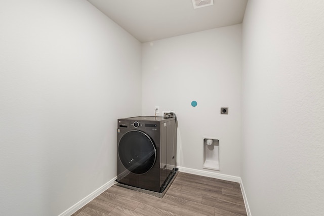 laundry room featuring light wood-style flooring, laundry area, visible vents, baseboards, and washer / clothes dryer