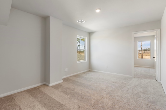 empty room featuring light carpet, visible vents, and a healthy amount of sunlight