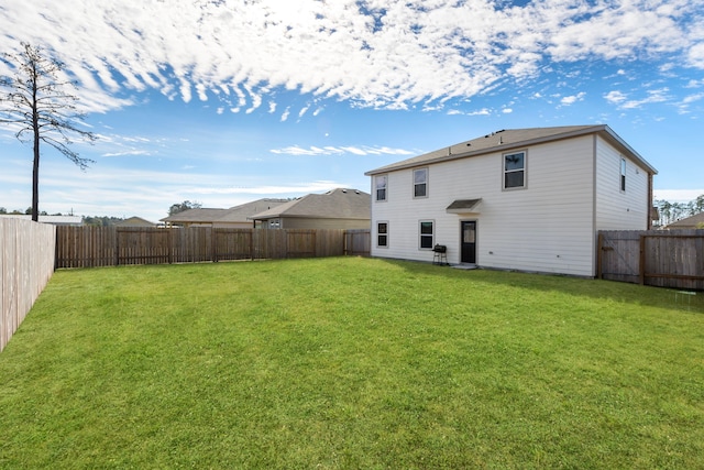 rear view of house with a fenced backyard and a lawn