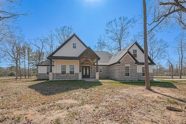 view of front of home featuring board and batten siding, stone siding, a shingled roof, and french doors