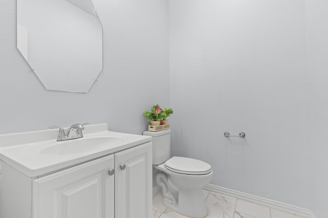 bathroom featuring toilet, marble finish floor, baseboards, and vanity