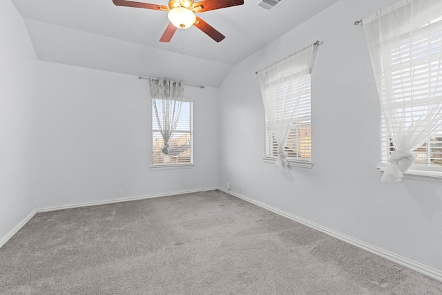 carpeted empty room featuring baseboards, visible vents, vaulted ceiling, and a ceiling fan